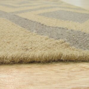 Close-up of a shaggy beige and gray geometric rug edge on a glossy light wood floor.