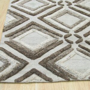 Beige rug with chunky raised brown and cream diamond patterns sits on light blonde wood planks.