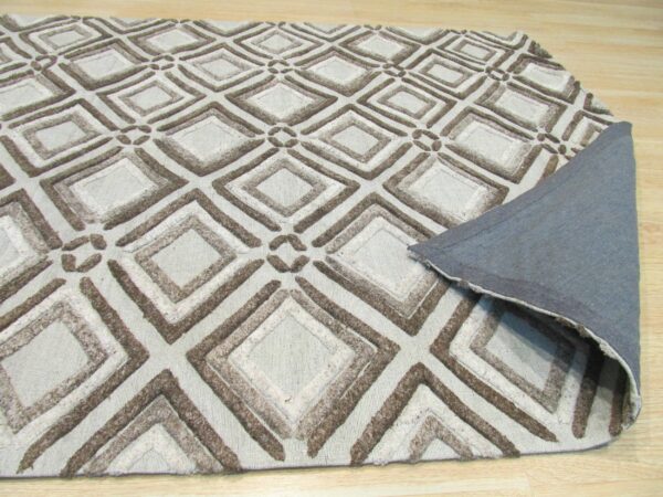 A light taupe rug with a textured brown geometric diamond pattern rests on wood flooring, showing its gray backing.