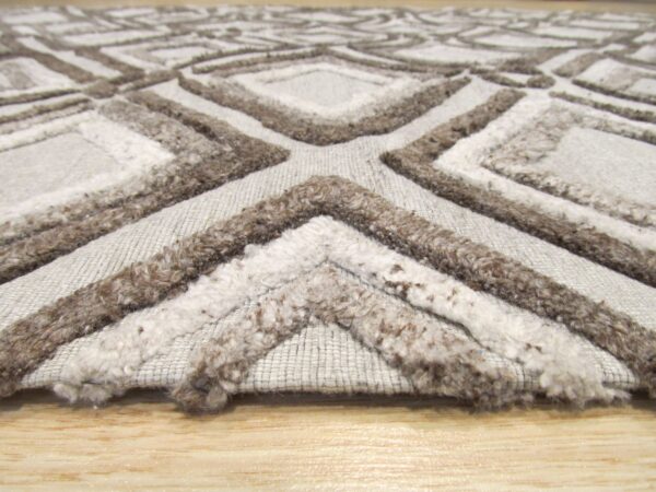 A textured gray rug with dark brown shaggy geometric patterns rests on light wood flooring.