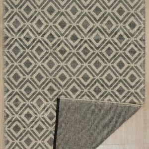 Geometric cream and dark gray rug featuring a diamond pattern, folded back to reveal the striped reverse side on wood flooring.