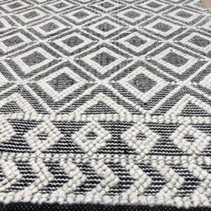 Textured black and white diamond pattern rug featuring contrasting flat and raised pile on light wood planks.