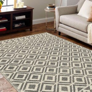 Geometric black and white rug anchoring a living room with a beige armchair and dark wood furniture.