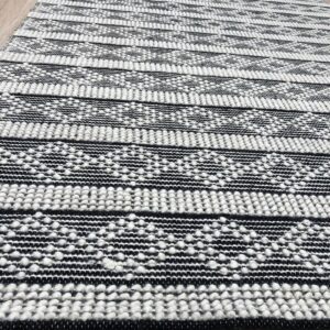 Black and white textured striped rug featuring raised knots on light wood plank flooring.