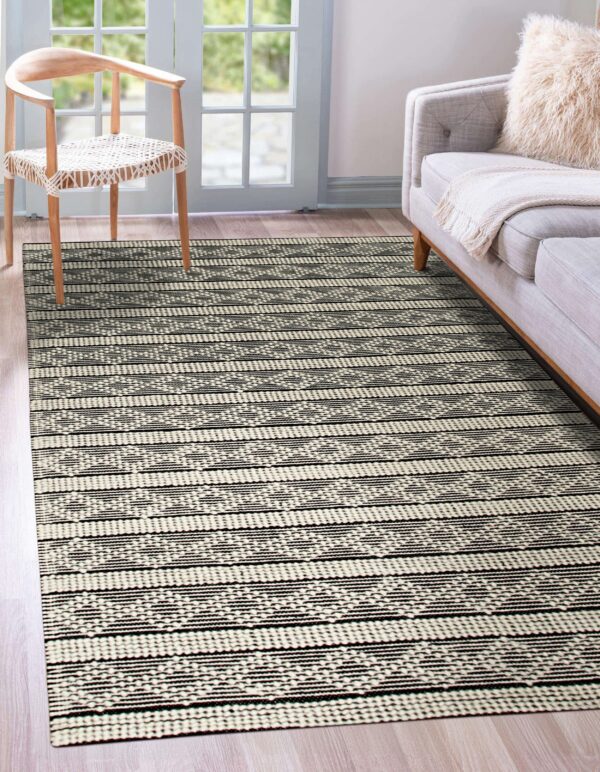 Black and ivory textured rug with geometric stripes under a wooden chair and gray couch.
