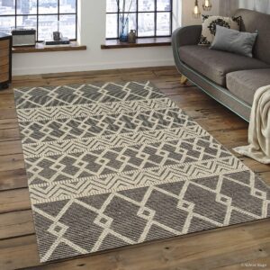 Black and beige flatweave rug featuring geometric diamonds and stripes on distressed wood flooring.