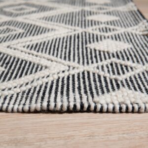 Black and cream geometric rug with textured loop accents rests on light wood flooring.
