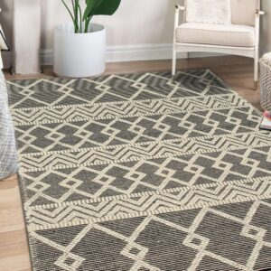 Geometric cream and dark gray flatwoven rug beneath a white chair and large indoor plant.