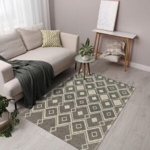 A black and beige geometric flatweave rug anchors a living area with a beige sofa and light wood flooring.