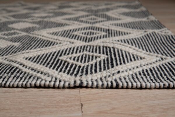 Black and cream chunky low pile rug featuring a geometric diamond pattern on light wood floor.