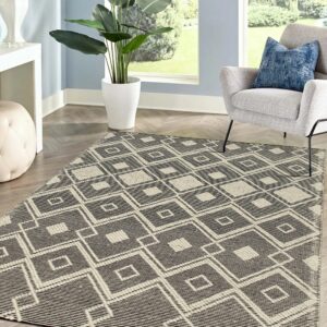 Black and off-white geometric diamond rug anchors a living area with a gray chair and herringbone wood floor.