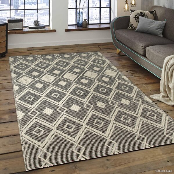 A flatweave black and cream rug with a geometric diamond pattern sits on rustic wood floors.