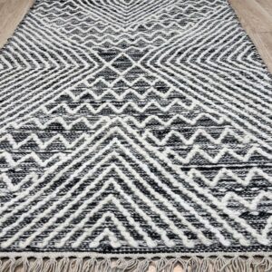 Black and white textured runner rug with fringe and geometric patterns on a light wood floor.