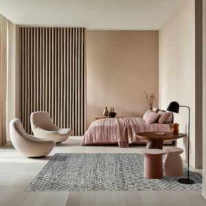 Geometric gray and white rug in a modern bedroom with pale pink walls, a slatted panel, and curved seating.