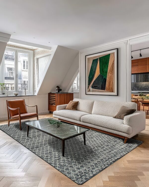 A gray geometric rug anchors a living room with a cream sofa and herringbone wood floor.