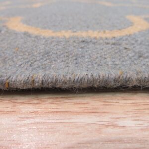 Textured gray-blue rug edge with pale orange accents rests on a light wood floor surface.