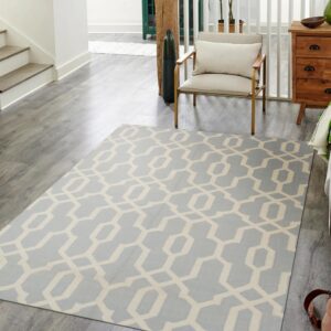 Light blue and cream geometric rug on grey wood floors in a bright hallway near a chair.