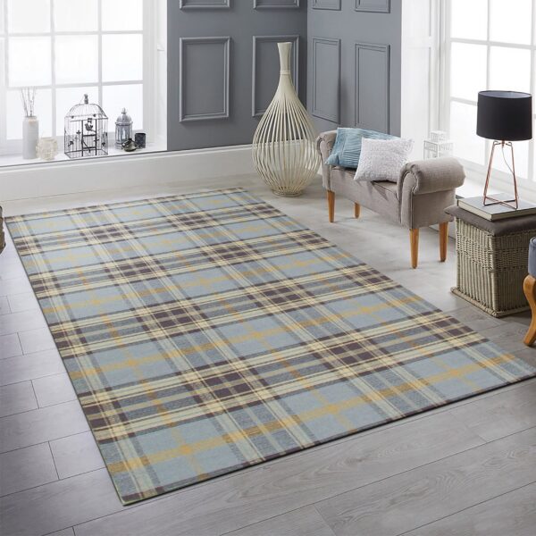 Plaid rug in blues, gold, and brown placed on gray plank floors in a sunlit room.
