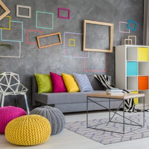 Geometric blue and beige area rug anchors a coffee table and gray sofa in a brightly lit modern room.