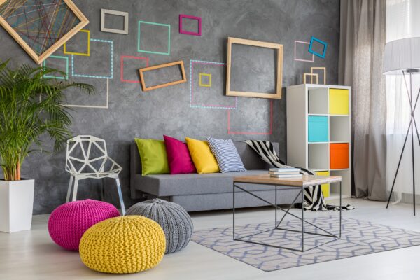 Geometric blue and beige area rug anchors a coffee table and gray sofa in a brightly lit modern room.