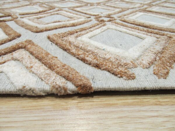 Raised cream and brown diamond patterns contrast with a flat gray background, visible atop light wood flooring.