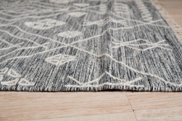 Textured gray rug with raised white geometric lines and diamonds rests on light wood floor.