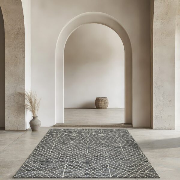 Gray rug with white geometric diamonds lies on light flooring under tall archways in a neutral space.