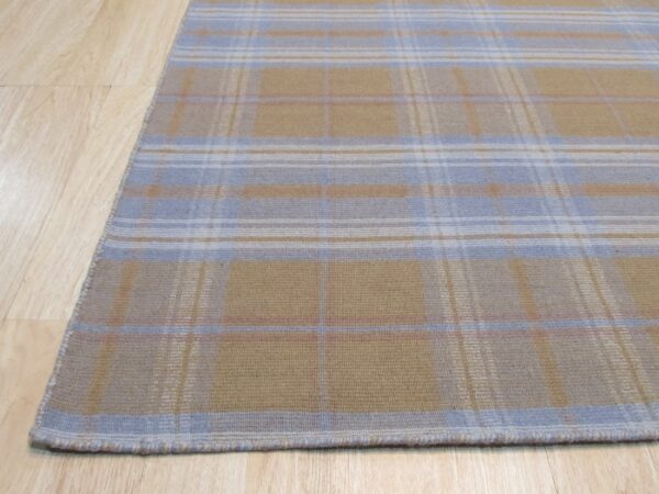 Tan and light blue plaid rug with woven texture lying on a light wood floor.