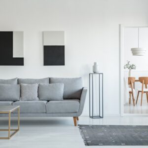 Dark gray flatweave rug featuring geometric white and blue patterns rests on a bright white floor.