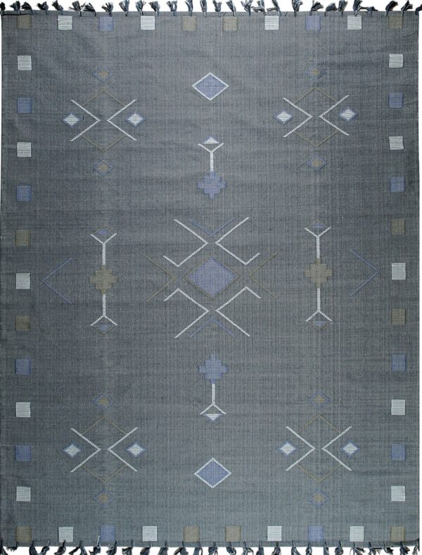 Charcoal gray flatweave rug with repeating blue, taupe, and white geometric patterns and dark tassels.