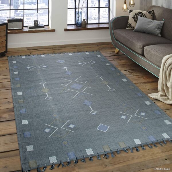 Low-pile gray rug with blue, white, and taupe geometric patterns sits on hardwood near a sofa.