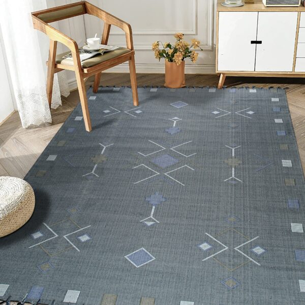 Flat gray rug with blue, white, and taupe geometric patterns shown in a naturally lit living area.