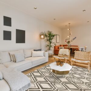 Geometric cream, gray, and black diamond pattern rug beneath a coffee table and white sectional sofa.