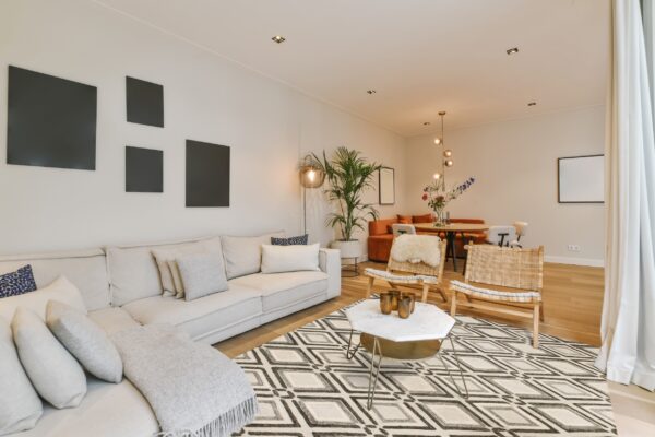 Geometric cream, gray, and black diamond pattern rug beneath a coffee table and white sectional sofa.