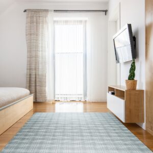 Light blue and white plaid rug spans a bright room with wood furniture and sheer curtains.