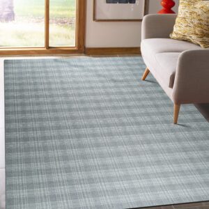 Muted slate blue plaid rug displayed on a dark wood floor beside a light-colored armchair.