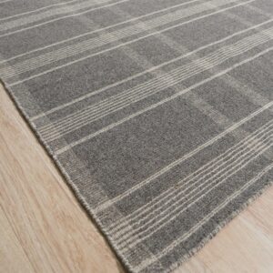 Gray low-pile rug with light plaid stripes angled across pale wood plank flooring.