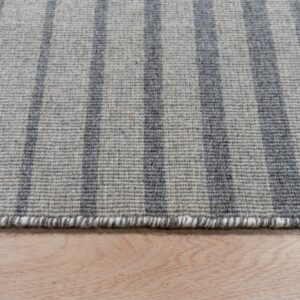 Light and dark gray striped rug with a textured low pile resting on blonde wood flooring.