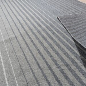 Light and dark gray striped rug on a wood floor, with the corner folded to show the reverse.