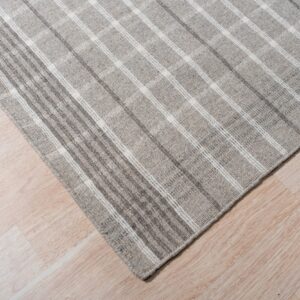A low pile gray rug with a subtle white plaid pattern rests on pale wood flooring.