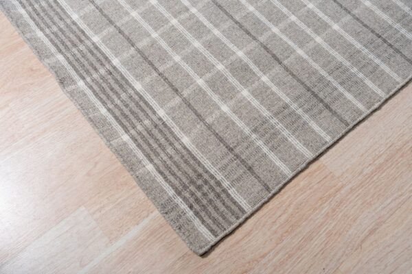 A low pile gray rug with a subtle white plaid pattern rests on pale wood flooring.