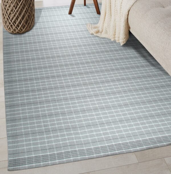 Gray checkered rug on light wood floor bordered by a woven basket and beige sofa.