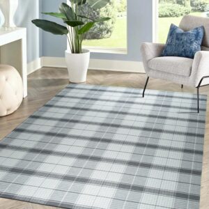 A gray and white plaid rug grounds a seating area with a gray chair on herringbone wood flooring.
