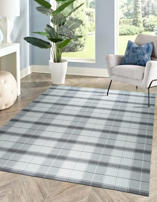 A gray and white plaid rug grounds a seating area with a gray chair on herringbone wood flooring.