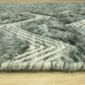 Close-up of a shaggy gray and white rug with a geometric chevron pattern resting on light wood flooring.