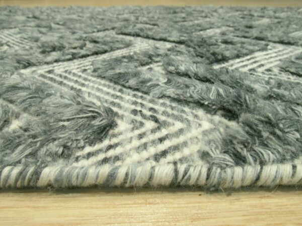 Close-up of a shaggy gray and white rug with a geometric chevron pattern resting on light wood flooring.