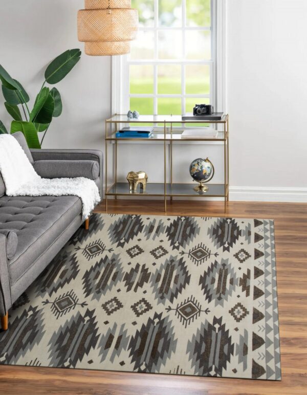 A cream rug with gray and brown geometric patterns covers wood floors beneath a gray sofa.