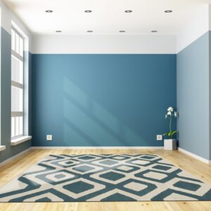 Teal and cream geometric rug centered on light hardwood floor against bold blue and white walls.