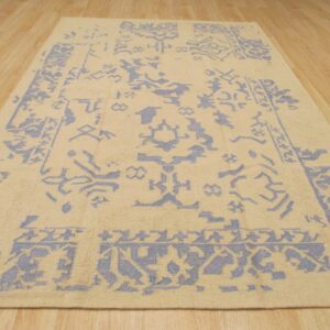 A tan and blue patterned rug with low pile rests on light wood plank flooring.