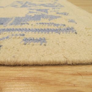 Extreme close-up of a low pile cream rug featuring a textured light blue loop pattern on wood flooring.